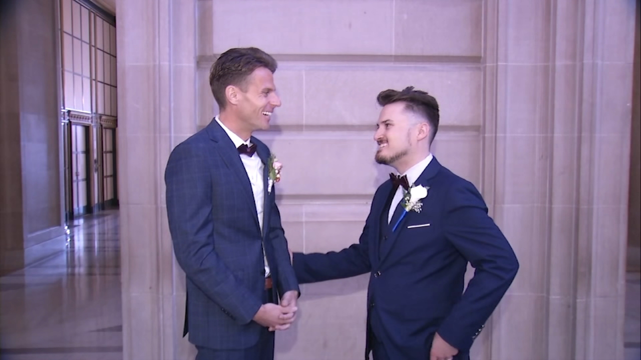 Source-feed image associated with Newlyweds celebrate Pride-themed weddings inside SF City Hall as parade preparations underway