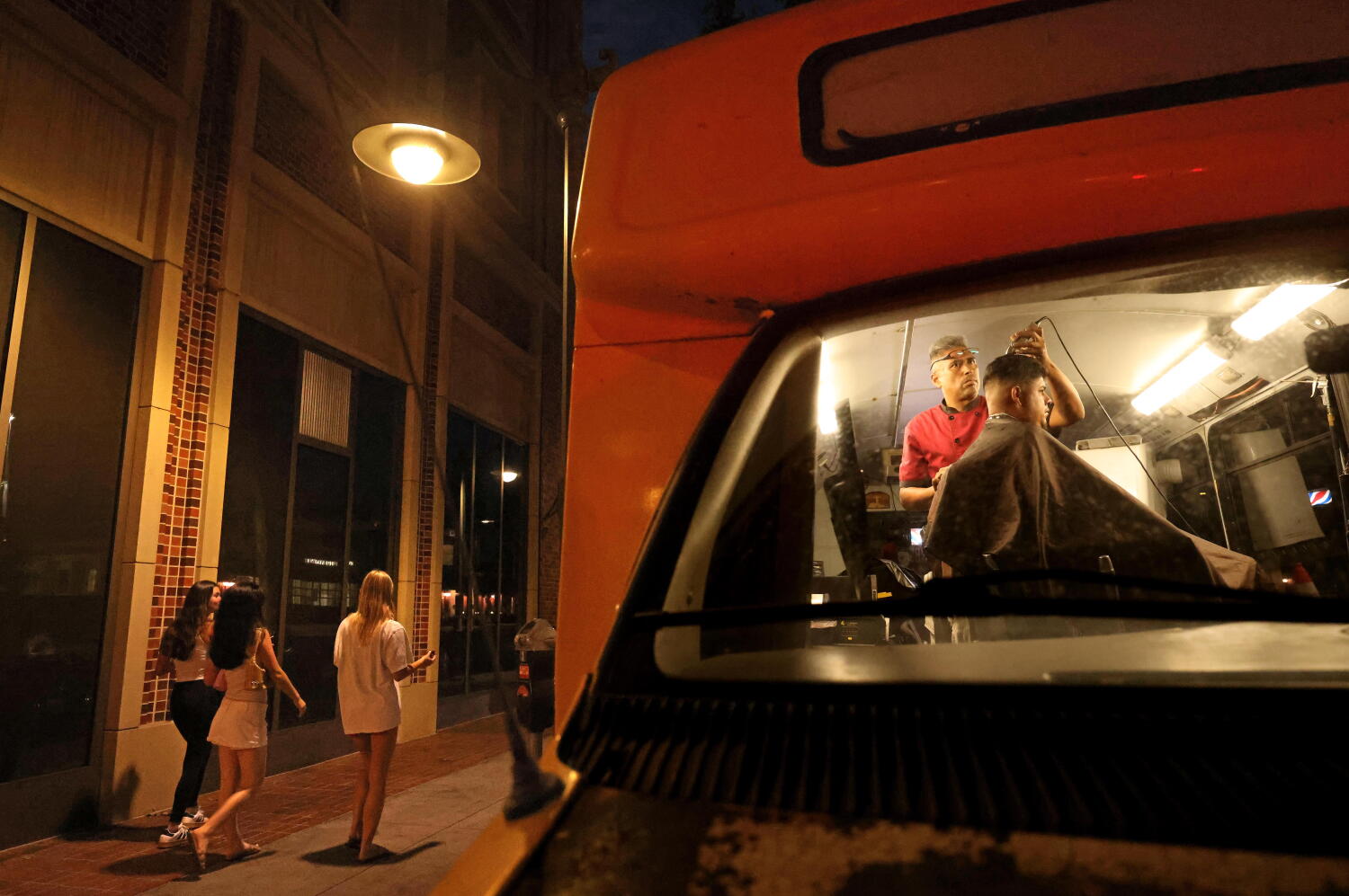 Source-feed image associated with USC students board Hector the Barber's school bus for curbside cuts