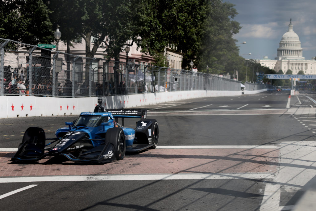 Source-feed image associated with Trump waves the green flag to start the IndyCar race as racers zoom through Washington's streets